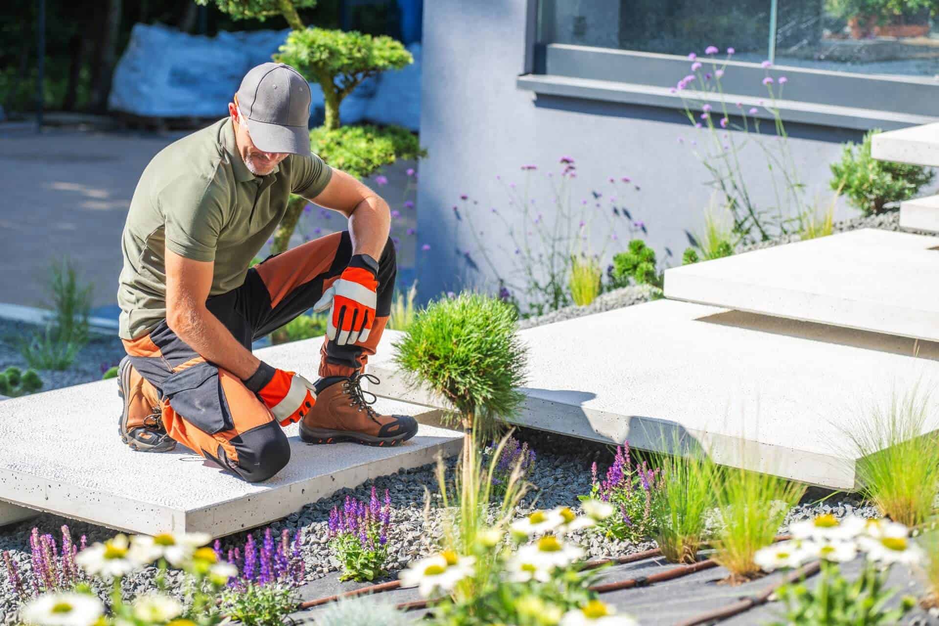 Gardener Kneels On Path Planting Flowers Ameristrong